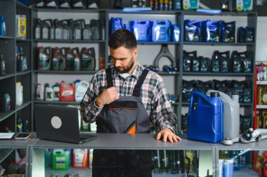 İş üniformalı bir tamirci elinde dizüstü bilgisayar ve kayganlaştırıcı, envanter ve işleme emirlerini kontrol ediyor.