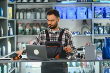 Bir otomobil parçası ve aksesuar mağazasında envanter yönetimi ve satışlar için barkod tarayıcı ve dizüstü bilgisayar kullanan servis çalışanı
