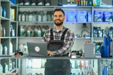 Otomobil parçaları satıcısı tezgahın arkasında duruyor, gülümsüyor ve yedek parça dükkanında iyi hizmet veriyor.