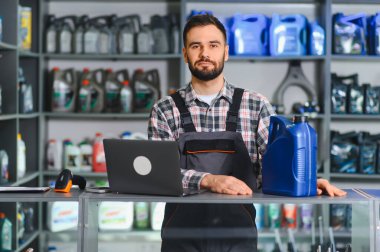 Servis yöneticisi bir otomotiv yedek parça dükkanında dizüstü bilgisayar kullanarak envanter ve satışları yönetiyor.