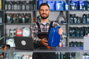 Araba parçaları reyonunda motor yağı satan gülümseyen tamirci, uzman otomotiv bakımı ve dostane hizmet sunuyor