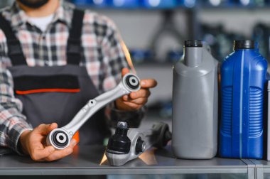 Tamirci, yeni kontrol kolunu başka bir bileşen ve motor yağı şişesiyle karşılaştırarak araba tamiri ve hizmet üzerine yoğunlaşıyor.