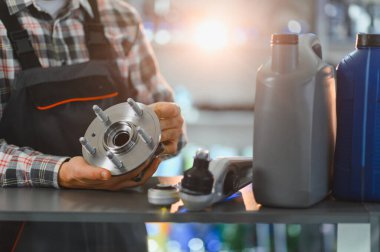 Tamirci yeni bir tekerlek merkezi ve diğer araba parçalarını tezgahta tutuyor. Otomobil servisi ve araç bakımı kavramı