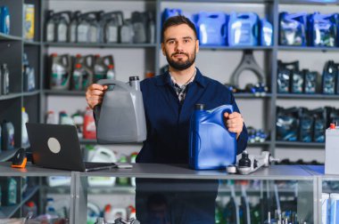 Motor yağı kutularını sunan tamirci veya mağaza asistanı, araç bakımı ve hizmet için otomotiv yağları sunuyor