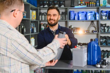 Bir müşteriye bir şişe araba motoru yağı sunan tamirci mükemmel hizmet ve ürün tavsiyesi sunuyor.