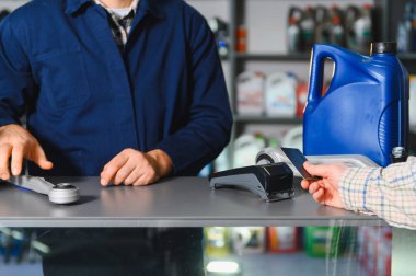 Müşteri oto yedek parça ve motor yağını araba tamirhanesindeki ödeme terminalinde kredi kartıyla ödüyor.