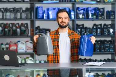 Bir otomotiv dükkanında motor bakımı için farklı türde kayganlaştırıcı sunan perakende işçisi