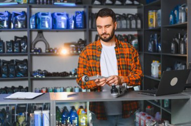 Araba süspansiyon kolu tutan erkek girişimci, bir oto yedek parça mağazasında detaylarına bakıyor.