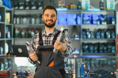 Otomobil tamircisi yeni araba süspansiyon parçaları sunuyor, yoğun bir otomotiv tamiri ve yedek parça dükkanında gülümsüyor