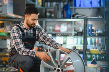 Servis çalışanı yeni bir otomobilin çevresini dikkatlice inceleyerek, bir dükkanda profesyonel otomotiv onarımı ve bakımı sağlar.