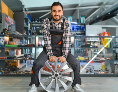 Araba jantını tutan tamirci, oto yedek parça dükkanında araç bakım ve onarım hizmeti sunuyor.