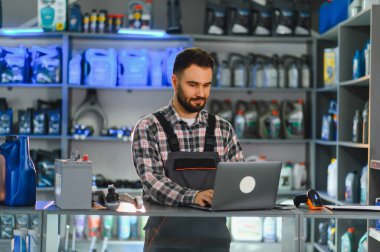 Bir otomotiv veya oto yedek parça mağazasında envanter yönetimi için dizüstü bilgisayar kullanan bir tamirci. Teknoloji ve profesyonel hizmete odaklanma