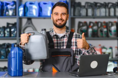 Motor yağı tenekesi tutan tamirci, profesyonel araba servisi ve bakım hizmetlerini işaret ediyor.