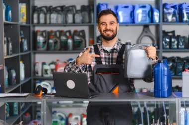 Araba tamircisi bir şişe kayganlaştırıcıyı göstererek müşterilere araba bakım ürünlerini açıklıyor.