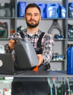 Otomotiv işçisi araba motoru yağı tavsiye ediyor. Dükkan tezgahından dizüstü bilgisayarla müşteri alımı hazırlanıyor