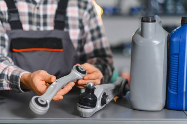 Yeni araba kontrol kolu tutan tamirci, bir otomotiv atölyesinde süspansiyon onarımı ve bakım için hazırlanıyor.
