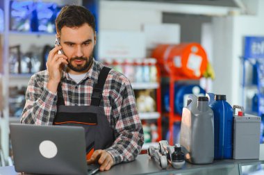 Erkek işçi müşterilerine sipariş alıyor veya hizmet veriyor, atölyede veya perakende mağazasında otomobil parçaları ve tamirat yönetiyor