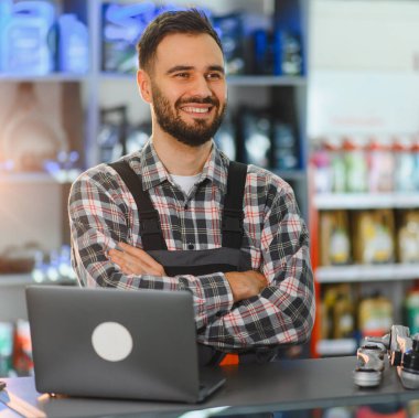 Otomobil parçaları dükkanında duran mutlu sakallı tamirci. Profesyonel hizmet ve destek sağlayan adam