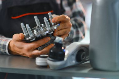 Tamirci yeni bir araba tekerleği merkezini kontrol ediyor, oto tamirhanesinde veya yedek parça mağazasında otomotiv tamiri için hazırlanıyor