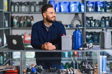 Araba yedek parça mağazasında çalışan gülümseyen adam, araç bakımı için yedek parça ve araç hizmeti veriyor.