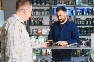 Tamircide yeni yedek parça ve motor yağı tedariği için irtibatsız kredi kartı ödemesi yapan tamirci asistanı