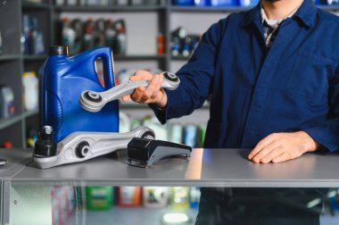 Tamirci araba süspansiyon kontrol kolu ve motor yağını otomotiv tamir servisinde sunuyor.