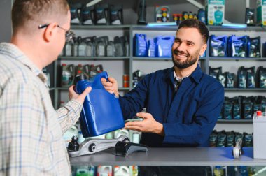 Tamirci, bir otomotiv parçası mağazasından motor yağı ve araba parçaları almada müşteriye yardım ediyor