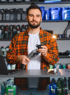 Ekose gömlekli sakallı tamirci araba süspansiyon kontrol kolunu ve topları kontrol ederken oto yedek parça dükkanında kendine güvenen uzman.