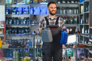 Otomobil tamircisi iki şişe motor yağı sunuyor, araba parçaları mağazasında otomotiv hizmeti ve bakım sunuyor