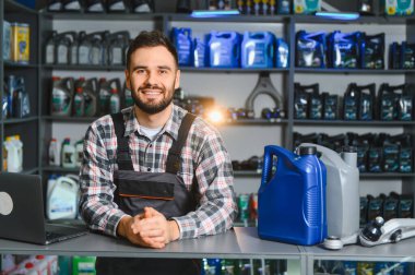 Gülümseyen tamirci oto yedek parça dükkanında müşterilere motor yağı ve araba servisi çözümleri sunuyor.