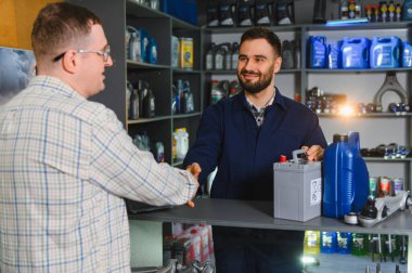 Profesyonel tamirci servis merkezinde araba aküsü ve motor yağı sunan oto yedek parça istemcisi alıyor