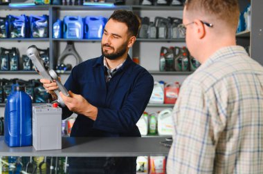 Bir otomotiv tedarikçisi dükkanında araba parçası dayanıklılığı ve seçimi konusunda müşteriye tavsiyede bulunan oto yedek parça satıcısı