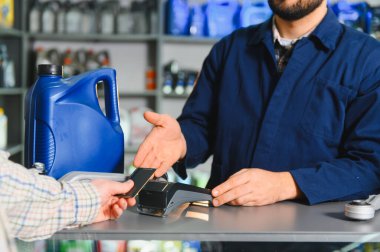 Otomotiv parçaları ve hizmet için ödeme yapan müşteri bir oto tamirhanesinde kredi kartı terminali kullanıyor.