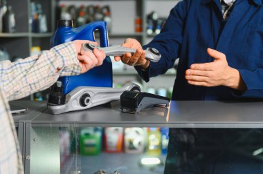 Otomobil parçaları işçisi müşteriye tezgahta yardım ediyor, bir perakende mağazasında araba süspansiyon kontrol kolu satıyor.