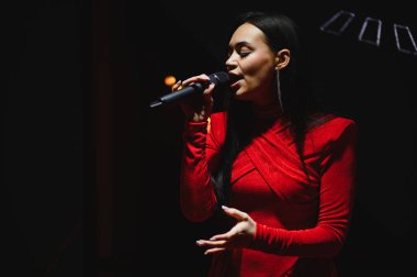 Kadın sanatçı, vokal yeteneğini ve sanatsal ifadesini paylaşıyor. Kalabalığı güçlü ve duygusal bir şarkıyla eğlendiriyor.