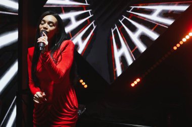 Sahnede konser veren kadın şarkıcı, canlı müzik performansı sırasında seyirciyi büyülüyor.