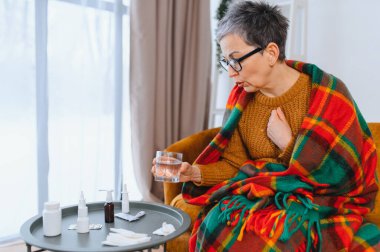 Yaşlı kadın kendini iyi hissetmiyor, sıcak bir battaniyeye sarılıp öksürük ya da nefes darlığı çekiyor.