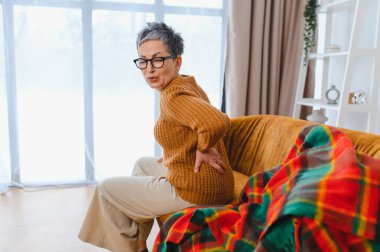 Olgun bir kadın rahat hissetmiyor ve beline dokunmuyor. Koltukta otururken kas zorlanması ya da ağrısı çekiyor.