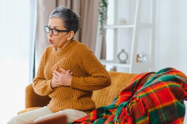Son sınıf öğrencisi kadın aniden göğüs ağrısı ve nefes almakta zorlanıyor. Göğsünü koltukta tutuyor.