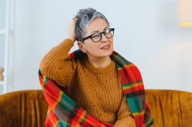 Şiddetli baş ağrısı ya da migren şikayeti olan gri saçlı yaşlı bir kadın.