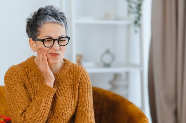 Son sınıf öğrencisi, dişleri ağrıdığı için el ele tutuşmuş. Diş hassasiyeti ve oral sağlık sorunları