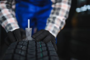 Tamirci güvenlik denetimi yapıyor, bir oto tamirhanesinde lastik izi derinliğini ölçüyor kazaların önlenmesine yardımcı oluyor.