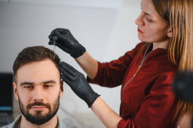 Trikoloji kliniğindeki bir damlacıktan saç büyütme serumu süren hasta.