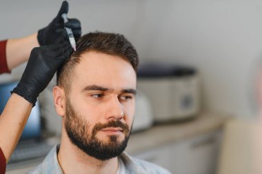 Klinikteki adam kafa derisi enjeksiyonu alıyor, saç dökülmesini tedavi ediyor ve saç uzamasını teşvik ediyor.
