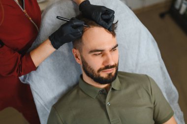 Erkek hasta saç tedavisi için trikoloğun birinden kafa derisi izi alıyor. Saç dökülmesi ve kelliğe değinildiğinde