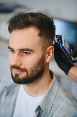 Detaylı bir trikolojik muayeneden geçen erkek hasta, kafa dermatoskop kullanarak kafa derisini ve saç foliküllerini analiz eden bir profesyonel.