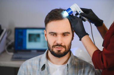 Saç sağlığı, teşhis ve saç dökülmesi tedavisi için ayrıntılı bir trikoskopi yapılan erkek hasta