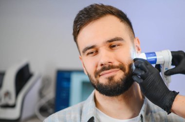 Hasta, dermatoloji kliniğinde sakalını ve yüz derisini detaylı bir şekilde incelemeye tabi tutuluyor.