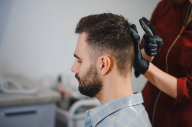 Sağlık uzmanı adamın kafasında benler ve deri sorunları var mı diye kontrol ediyor, onkoloji taraması ve erken teşhis üzerinde çalışıyor.