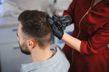 Dermatolog eldiven takıyor. Hastanın kafasını büyüteçle inceliyor. Kanser taraması ve cilt sağlığı konsepti